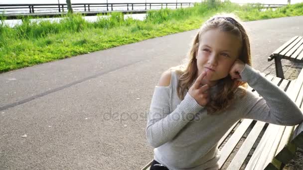 Menina falando no telefone com amigo, menina feliz no parque jogando no smartphone — Vídeo de Stock