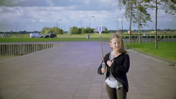 Flicka med bild på sig själv med telefon på selfie-stick — Stockvideo