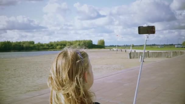 Flicka med bild på sig själv med telefon på selfie-stick — Stockvideo