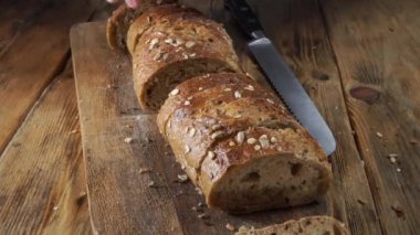 Closeup view. Chef cuts bread into slices on wooden cutting board
