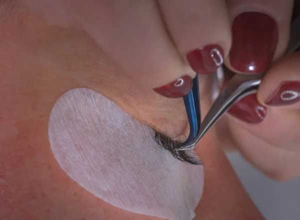 Pegando pestañas artificiales con pinzas. Procedimiento cosmético . — Foto de Stock