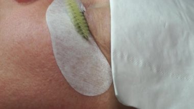 Yapay kirpikleri cımbızla yapıştırmak. Kozmetik prosedürü. Kirpik uzatma. Uzun kirpikli kadın gözü