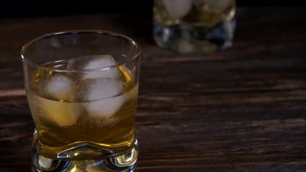  A jégkockák beleesnek egy pohárba arany maláta whiskyvel.