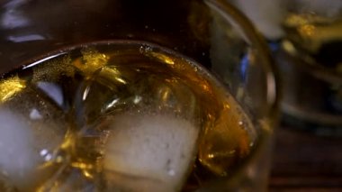 Buz küpleri altın viskiyle dolu bir bardağa düşer.