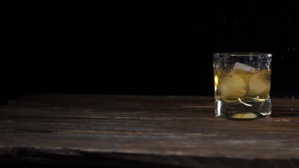 A jégkockák beleesnek egy pohárba arany maláta whiskyvel. 