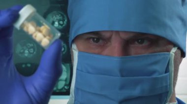  Koruyucu tıbbi maskeli bir doktor elinde haplar tutuyor. Tıp ve bilim araştırmaları.