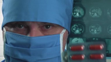Koruyucu tıbbi maskeli bir doktor elinde haplar tutuyor. Tıp ve bilim araştırmaları.
