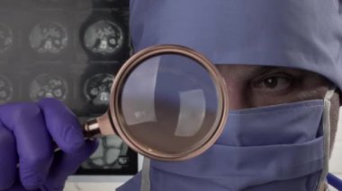 Kapatın. Koruyucu tıbbi maske ve tıbbi eldiven takmış bir doktor elinde büyüteçle pasif muayene ediyor.
