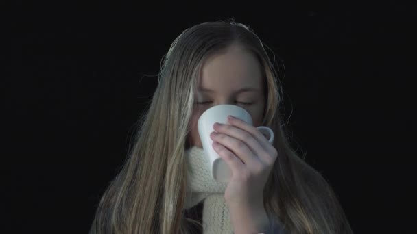 可爱的女孩试著暖暖身子 喝着热饮料 拿着杯子 在黑色的背景上带着可爱的笑容 — 图库视频影像