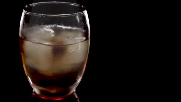接近中だ 氷のキューブが回転し ウイスキーのガラスに溶けます 白い背景に隔離されている 黒を背景にウイスキーでアイスバスを回転させる — ストック動画