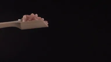 Pembe Himalaya tuzu, siyah arka planda tepeden tırnağa ahşap bir kepçeden yavaş çekimde eklenir.