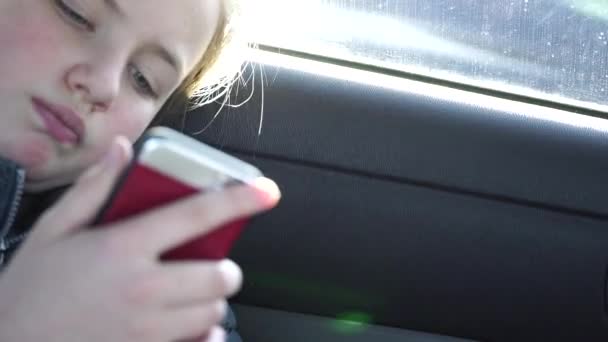靠近点悲伤的女孩在车里无聊地看着智能手机 — 图库视频影像