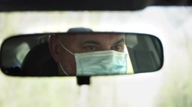 Ölüm nedeni 19. Steril tıbbi maskeli bir adam araba kullanıyor. Yerel halk araba sürerken tıbbi maske kullanıyor. Karantina viral enfeksiyonu.