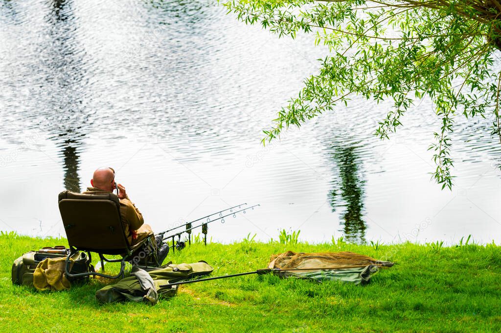 A fisherman is talking on the smartphone while fishing.
