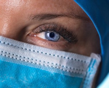 Maskeli yorgun doktor kameraya bakıyor. Kapatın. Seçici odak