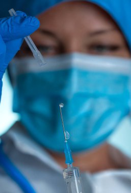 Kadın doktor covid-19 aşısı yapmaya hazır. Mavi nitrili Doktor 'un ellerinde tıbbi lastik eldivenler tıbbi şırınga tutuyor.