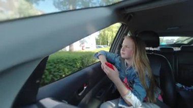 Sıkıcı kız arabaya biner ve pencereye bakar. Üzgün yüzlü kız, arabada otur.