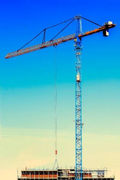 Tower crane and building construction on a background of blue sk
