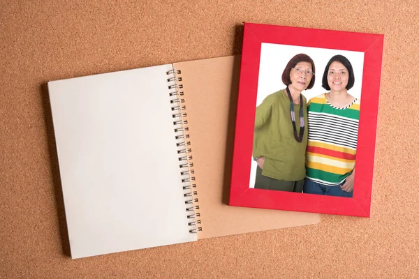 note book and  frame with picture of mom and daughter on wooden