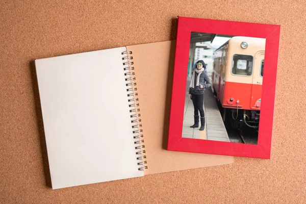 Note book and picture of woman in frame on wooden table — Stock Photo, Image