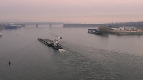 空中风景 一艘老拖船在黎明时分慢慢地把一艘驳船推下一条小河 浓雾从光滑的水面上美丽地扩散和反射出来 在河上工作的运输船 — 图库视频影像