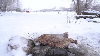 Karla kaplı bir nehrin kıyısında ev yapımı barbekü, pişirme, balık tutma.