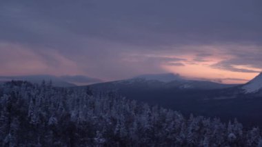 Güneşli bir kış gününde karlı dağların manzarası, tepelerinde karla kaplı köknar ağaçları, kış masalı.