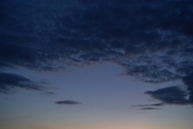 Gün batımında parlayan parlak ışık bulutlarıyla güzel bir akşam mavisi gökyüzü. Sıcak bir akşam. Nisan. Mayıs.