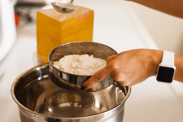 Woman adding salt to flour. Woman doing homemade pizza. Dressed in white pinny