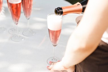 Şampanyayı şarap bardağına dolduran adam