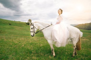 Güzel bir gelin beyaz bir ata biner çayırda
