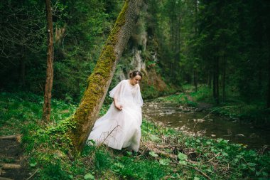 Doğada poz veren beyaz elbiseli güzel gelin