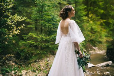 Doğada poz veren beyaz elbiseli güzel gelin