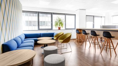 iş merkezinde mavi koltukları ve yuvarlak masaları olan modern iç mekan.