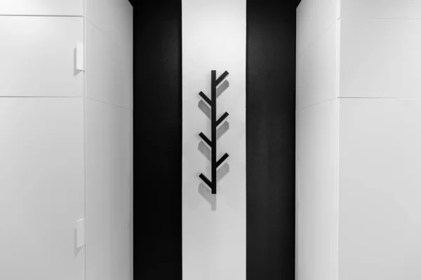 Siyah elbise askısı beyaz bir duvarda ağaç şeklinde.