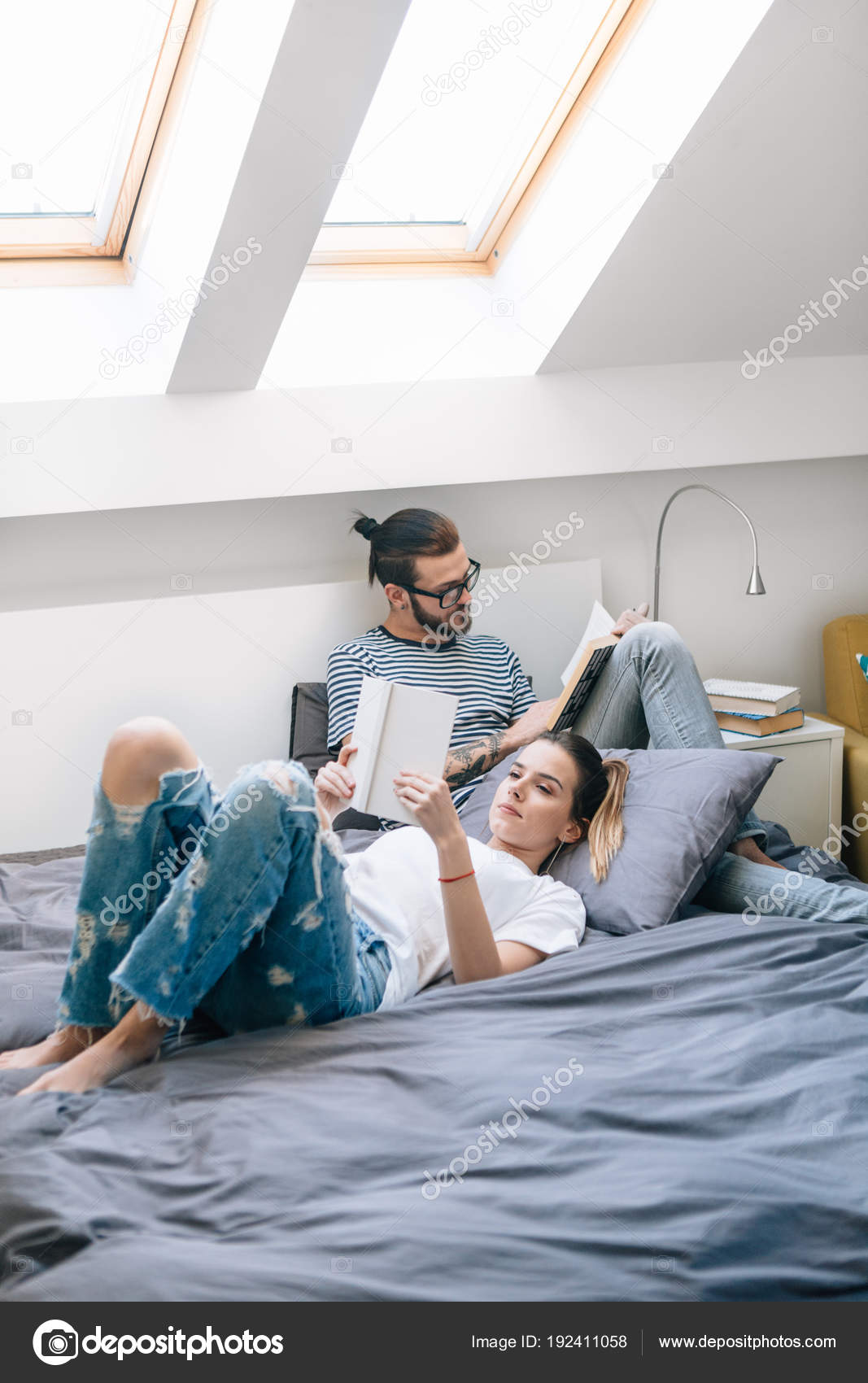 attractive stylish couple read books bed light room home stock