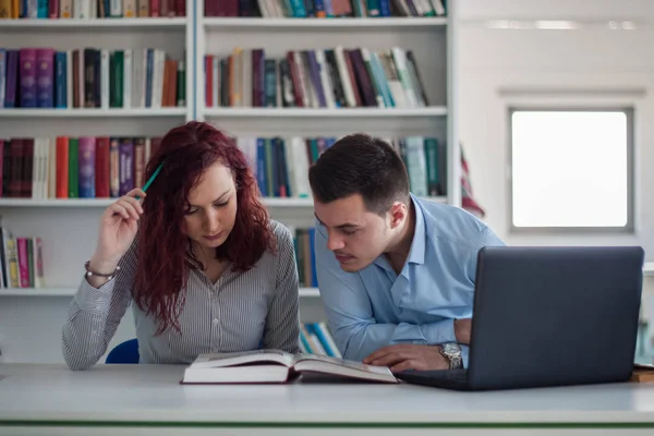 Guapo chico y hermosa pelirroja estudiando en la biblioteca — Foto de Stock