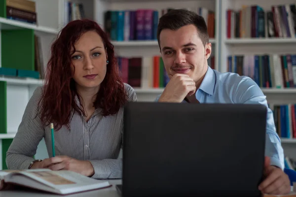 Schöner Kerl und schöne rothaarige Mädchen studieren in der Bibliothek — Stockfoto