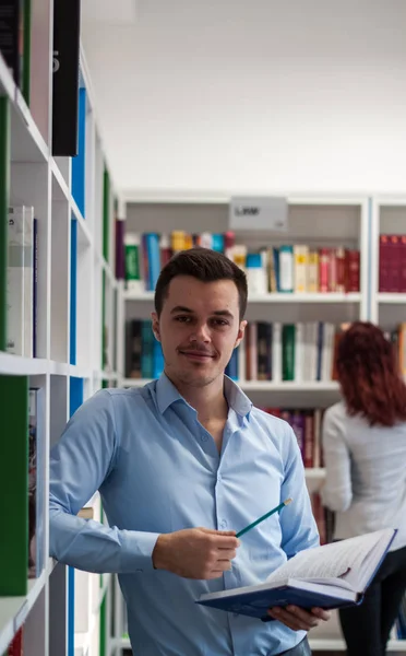 Guapo morena estudiante chico sentado en el escritorio y mirando fa — Foto de Stock