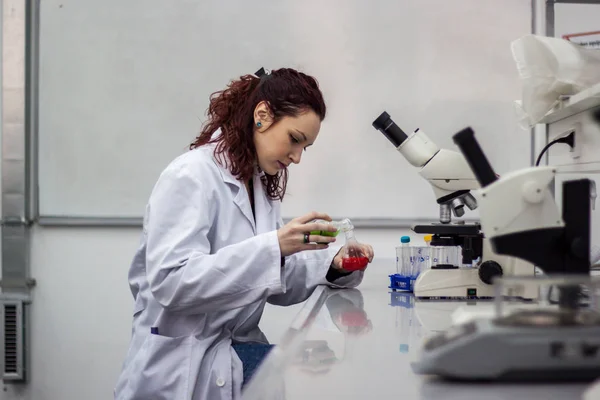 Researcher or scientist or doctoral student pours red and green