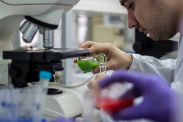 Researcher or scientist or doctoral student pours red and green — Stock Photo, Image