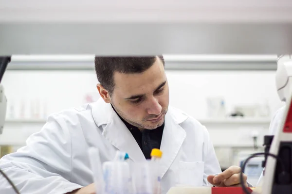 Young doctor conducts research, and it is very concentrated and — Stock Photo, Image