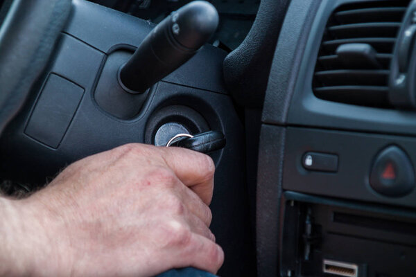 The driver is about to start the car, holds the key in his hand 