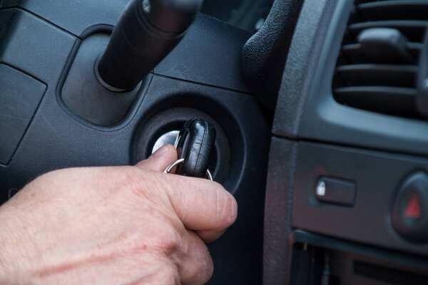 The driver is about to start the car, holds the key in his hand 