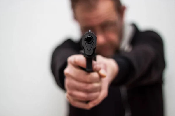 Mannen håller pistolen i hans händer och målet till en annan person, — Stockfoto