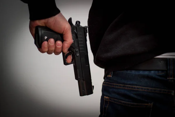 Killer håller en pistol till hans fötter, vit bakgrund framför h — Stockfoto