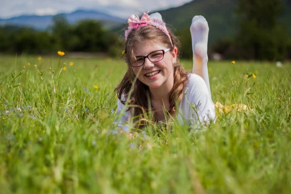 Bella ragazza bionda seduta su una bella erba verde piena di — Foto Stock