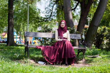 Güzel kız güzel bir elbise içinde kaplı oturur bir parkta bir 