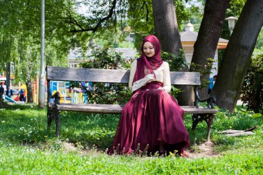 Güzel kız güzel bir elbise içinde kaplı oturur bir parkta bir 