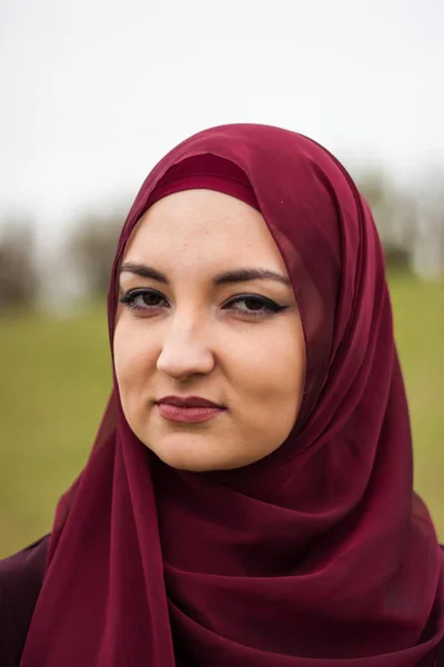 Young and beautiful girl covered, Muslim, in burgundy dress, wal
